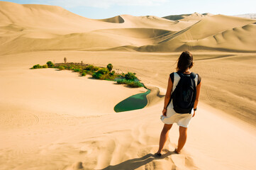 woman crossing The Huacachina Oasis, in the desert sand dunes near the city of Ica, Peru