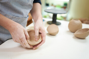 Obraz na płótnie Canvas woman forming clay pot shape by hands, closeup in artistic studio