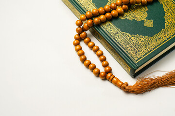 The Holy Al Quran with written arabic calligraphy meaning of Al Quran and rosary beads or tasbih on...
