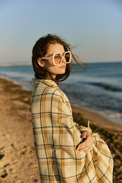 portrait of a beautiful woman with red hair blown by the wind on the sea coast wrapped in a plaid