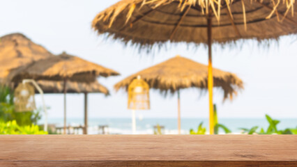 Fototapeta premium Empty wood table top and blurred seaside restaurant in tropical resort in summer banner background - can used for display or montage your products.
