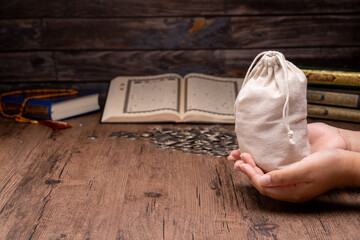 Hands holding a money bag for zakat, Islamic zakat concept. Muslims help the poor and needy....