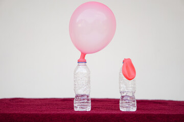 Science experiment , inflated balloons and flat balloon  on top of transparent test bottles....