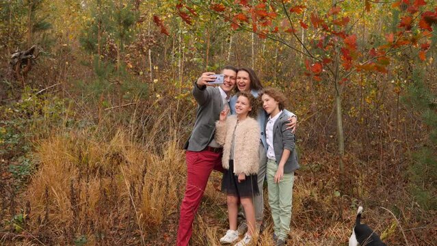 Happy family parents with children taking smartphone selfie picture on beautiful autumn forest nature