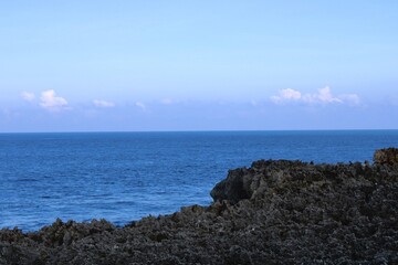 View from an observation deck of a straight line horizon of the Indian ocean cutting the clear skies with jagged limestone edges below. 