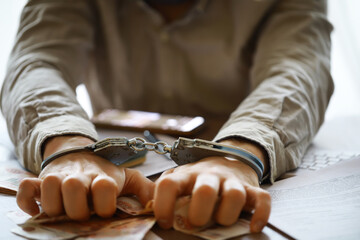 Hands in handcuffs behind, holding five thousand rubles. Concept of corruption