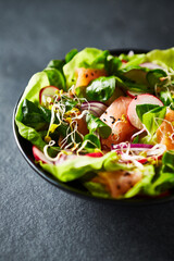 Salmon salad with leaf vegetables, radishes and sprouts