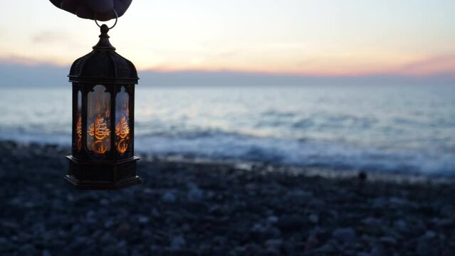 Muslim traditional lantern glows on the seashore at sunset,copy space