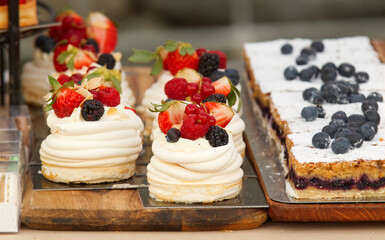 Pavlova desserts embellished with summer berries fruits, raspberries, strawberries, blueberries and currant. Dessert at the stall at Prague farmers street food market.