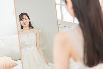 鏡を見ながら結婚式のウェディングドレスの衣装合わせ・試着をする花嫁
