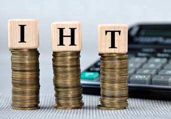 IHT - acronym on wooden cubes on the background of coins and calculator
