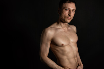 Fototapeta na wymiar Adult attractive man with a beautiful body posing in the studio. Black background.