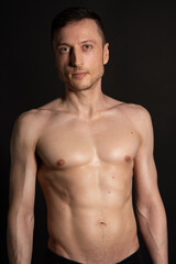 Fototapeta na wymiar Adult attractive man with a beautiful body posing in the studio. Black background.
