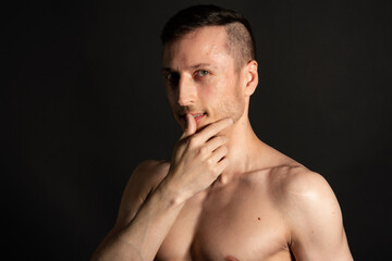 Fototapeta premium Adult attractive man with a beautiful body posing in the studio. Black background.