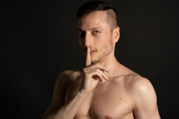 Naklejka premium Adult attractive man with a beautiful body posing in the studio. Black background.