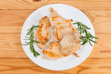 Grilled chicken steaks with fresh rosemary twigs on a dish