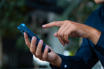 Businessman finger touch smartphone on blurred background, closeup