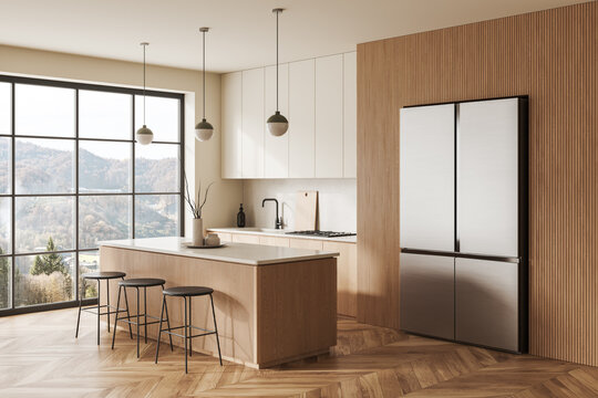 Light kitchen interior with bar island, fridge and cooking area, panoramic window