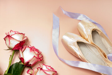 ballet slippers lying on pink background with roses and ribbons. elegant ballet shoes bouquet. beauty dance