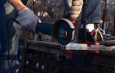Cut aluminum profiles. A master at work gloves saws off the aluminum profile with an angle grinder.
