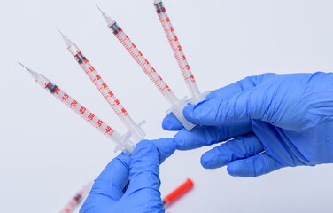 strzykawki z insuliną trzymane w dłoniach pielęgniarki w niebieskich rękawiczkach medycznych
