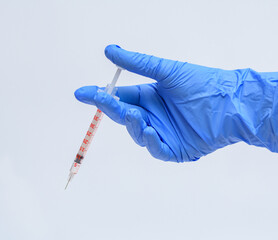 Szczepionka trzymana w dłoni w niebieskiej rękawiczce na białym tle - obrazy, fototapety, plakaty