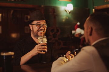 man is having fun chatting with a bartender in bar counter while drinking beer from a glass in a pub