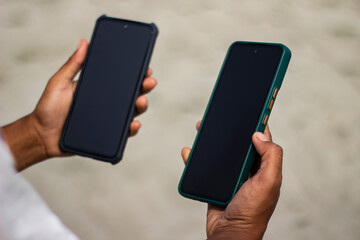 A boy is holding two mobile phones and the screen is black