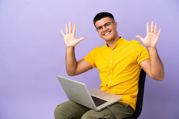 Young man sitting on a chair with laptop counting ten with fingers