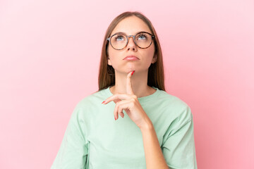 Young Lithuanian woman isolated on pink background With glasses and looking up