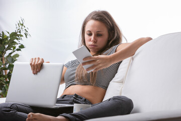 Young woman on couch, disrupted multitasking - obrazy, fototapety, plakaty