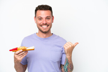 Young caucasian man holding sashimi isolated on white background pointing to the side to present a product