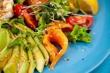 Healthy breakfast. Avocado and salmon toast, salad and vegetables. Microgreens on a plate. Food bowl. Lunch on a blue plate. Sauce and sesame seeds, lemon tomatoes. Top view.