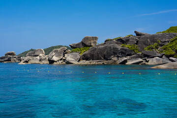 Tropical island of Andaman coast with turquoise and clear blue waters against blue sky.