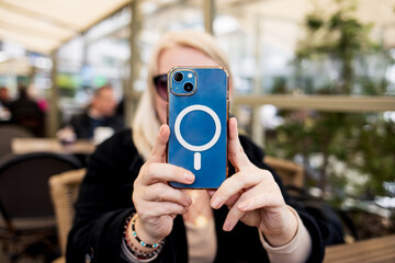 Middle aged woman entrepreneur with smartphone sitting in a street cafe.