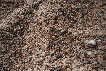 Dark brown natural texture of tiny beige beach pebbles.
