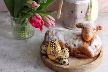 Easter cake in the shape of a lamb with Easter eggs and spring flowers on the table