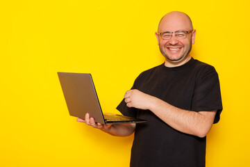 Male freelancer holding laptop computer on yellow background