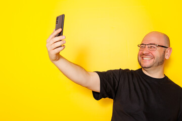 Man taking a selfie isolated on yellow colored background - obrazy, fototapety, plakaty