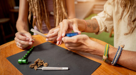 Hippie style couple making medical marijuana cigarettes