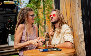Hippie style couple smoking medical marijuana using a bong