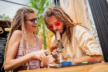 Hippie style couple smoking medical marijuana using a bong
