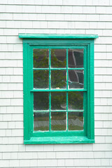 Old green window on white wash clapboard shingle house