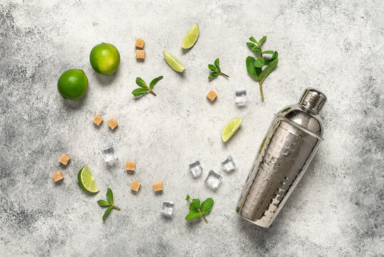 Ingredients for mojito frame, lime, mint leaves, shaker and cane sugar. Light gray vintage background. Top view, flat lay, copy space.