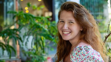 portrait of a cute girl in glasses in a cozy green cafe smiles, rests, relaxes and looks at the camera