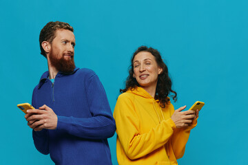 Woman and man cheerful couple with phones in their hands crooked smile cheerful, on blue...