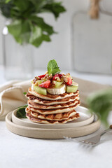 Stack of pancakes with strawberries and fruits.