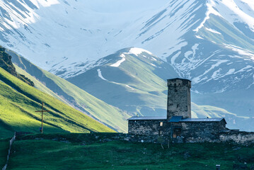 A single Svaneti defense tower in front of the snow-capped Caucasus mountains in Ushguli/ Georgian