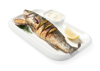 Plate with delicious baked sea bass fish, garlic, slice of lemon and sauce on white background