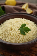 Tasty couscous with parsley on wooden board, closeup